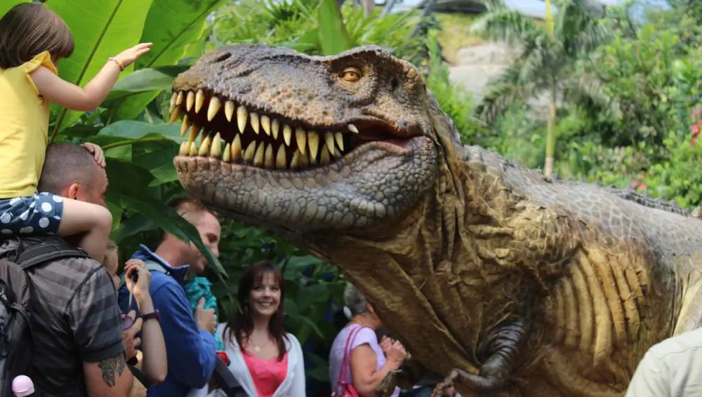Lifelike dinosaur costume close-up interaction with children at commercial event, showing realistic skin texture and animatronic head
