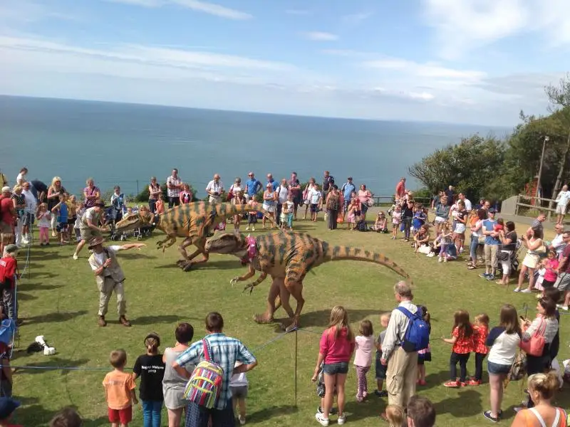 Outdoor dinosaur costume event with large crowd engagement, demonstrating commercial deployment success