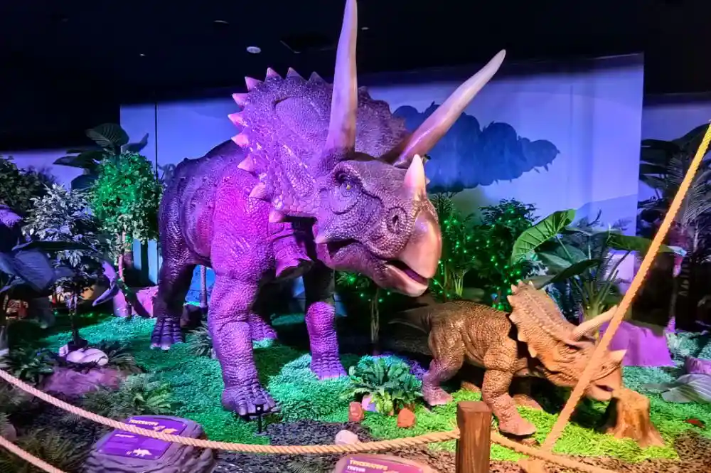 Small and large animatronic dinosaur comparison in museum exhibit layout