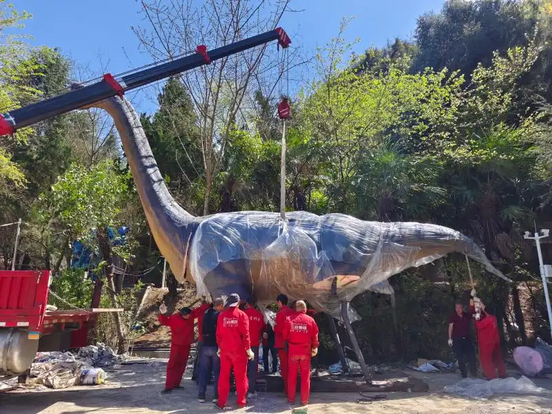 Crane and crew positioning a wrapped animatronic sauropod — installation and site work belong to the true cost to build a dinosaur attraction