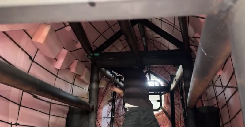Inside a large animatronic dinosaur: steel frame, padding, and a technician at work — the structure that carries animatronic dinosaur lifespan