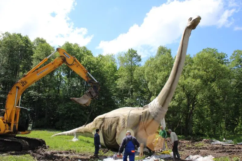 Large-scale animatronic sauropod installation with excavator at outdoor theme park project