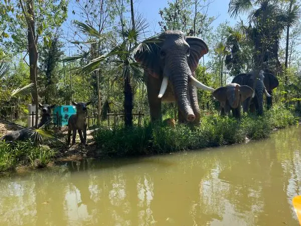 Diverse themed environments at an animatronic dinosaur park, featuring elephant animatronics and water features.