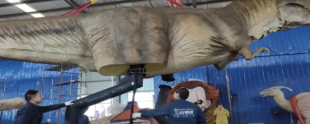 A suspended T. rex guided by Sanhe technicians during service — component-level animatronic repair and refurbishment under one roof