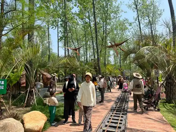 Busy visitor pathways with flying pterosaur animatronics at a successful dinosaur attraction.