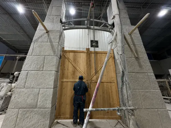 Factory pre-assembly of the massive stone-texture entrance gate for a turnkey dinosaur attraction.