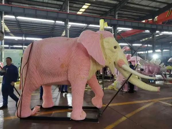 Detailed foam carving stage of a large animatronic elephant, showing the initial sculpting process for a dinosaur attraction design.